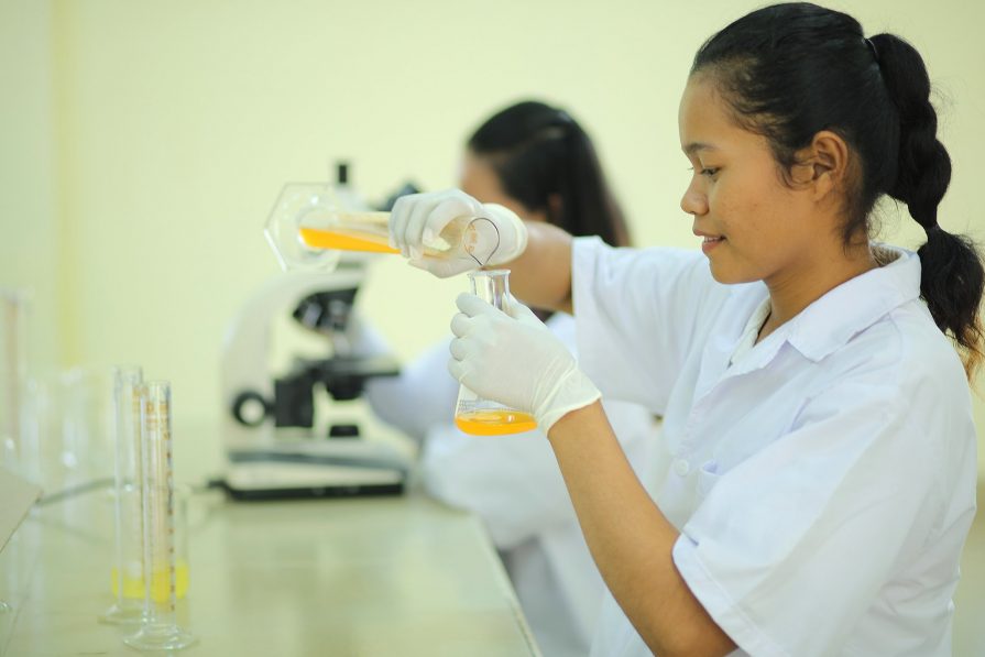 A Svay Rieng University student measures a liquid into a flask during a practical science course.