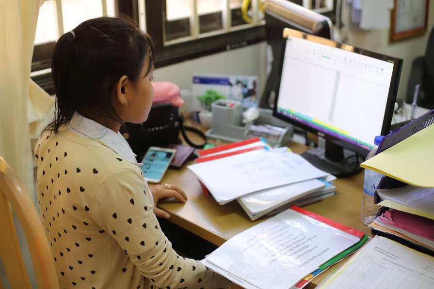 A female student works on a computer as an intern for one of Svay Rieng University's offices.