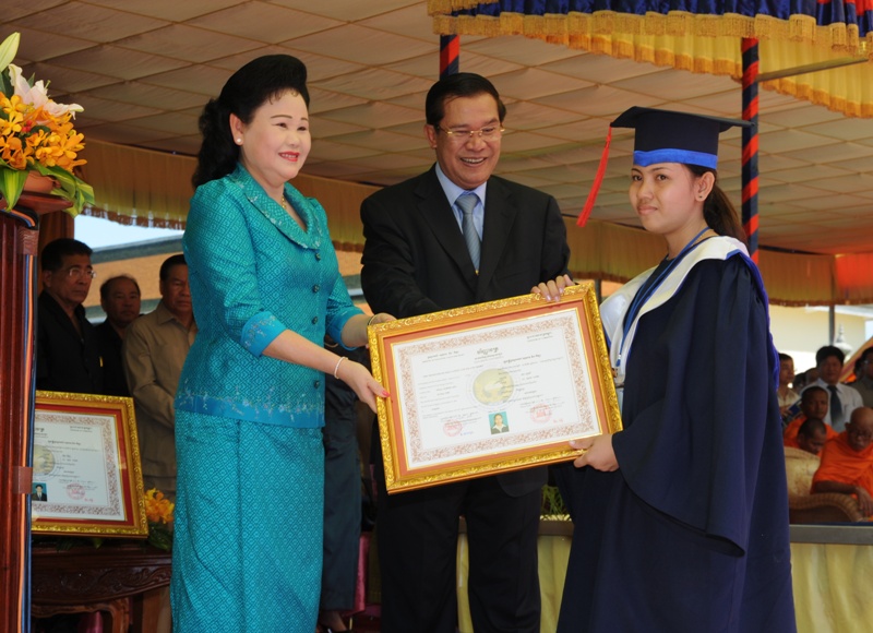 Prime Minister Hun Sen and Bun Rany hand a diploma to a member of Svay Rieng University's first graduating class